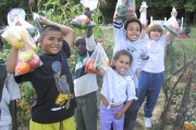 Children holding bags of vegetables.