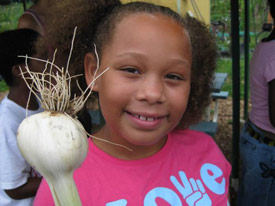 A girl holding a veggie.