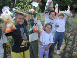 Kids holding bags of vegetables.