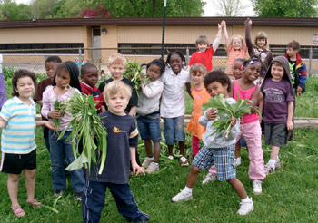 Kids in a group, some holding vegetables.